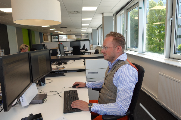 Een man die werkt als sales medewerker. Hij zit achter zijn computer op het kantoor in Amsterdam. 