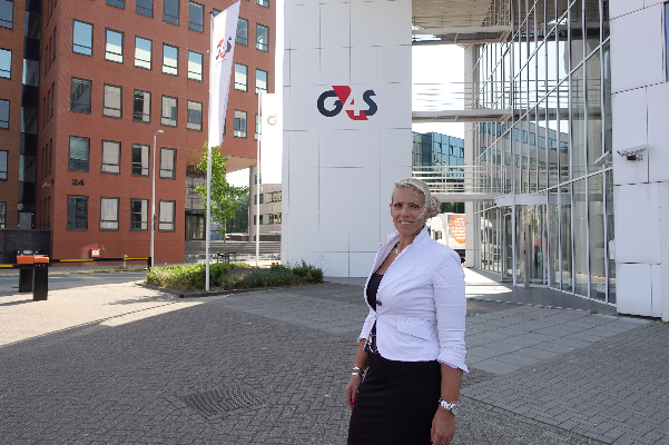 Een dame die in de sales werkt voor G4S. Zij staat voor het kantoor in Amsterdam waar zij werkt. 